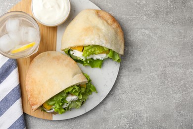 Delicious pita sandwiches with chicken breast and vegetables on light gray table, flat lay