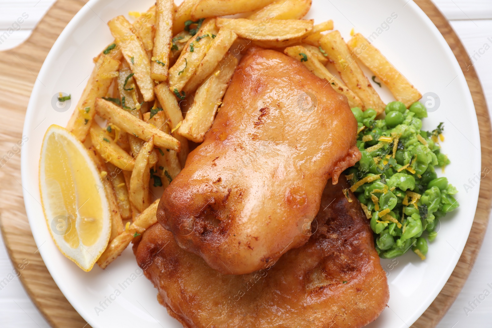 Photo of Tasty fish, chips, peas and lemon on white wooden table, top view