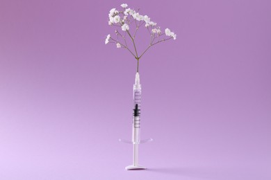 Photo of Cosmetology. Medical syringe and gypsophila on violet background