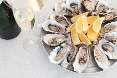 Photo of Fresh oysters with cut juicy lemon served on table, above view