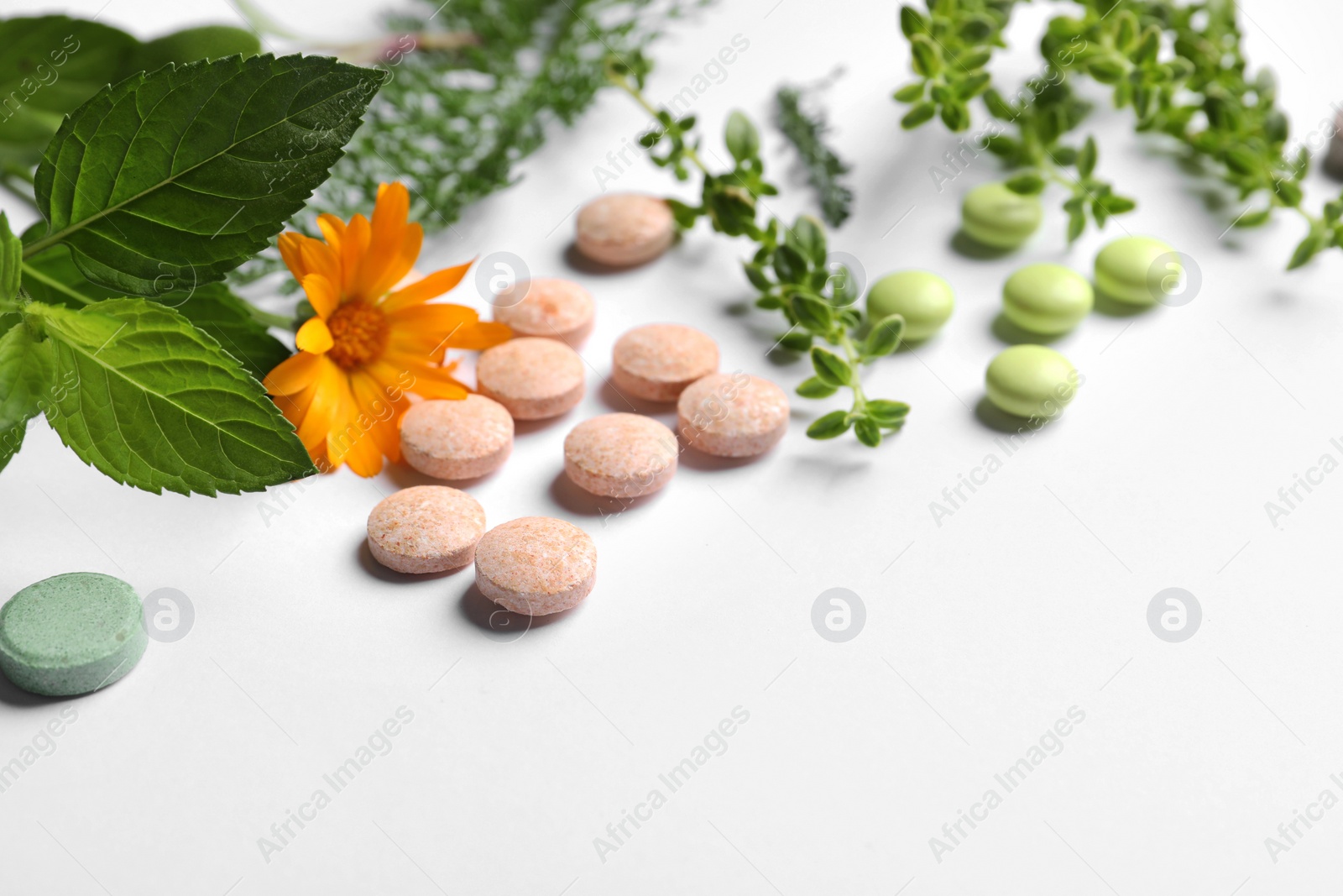 Photo of Different pills, herbs and flower on white background, closeup with space for text. Dietary supplements