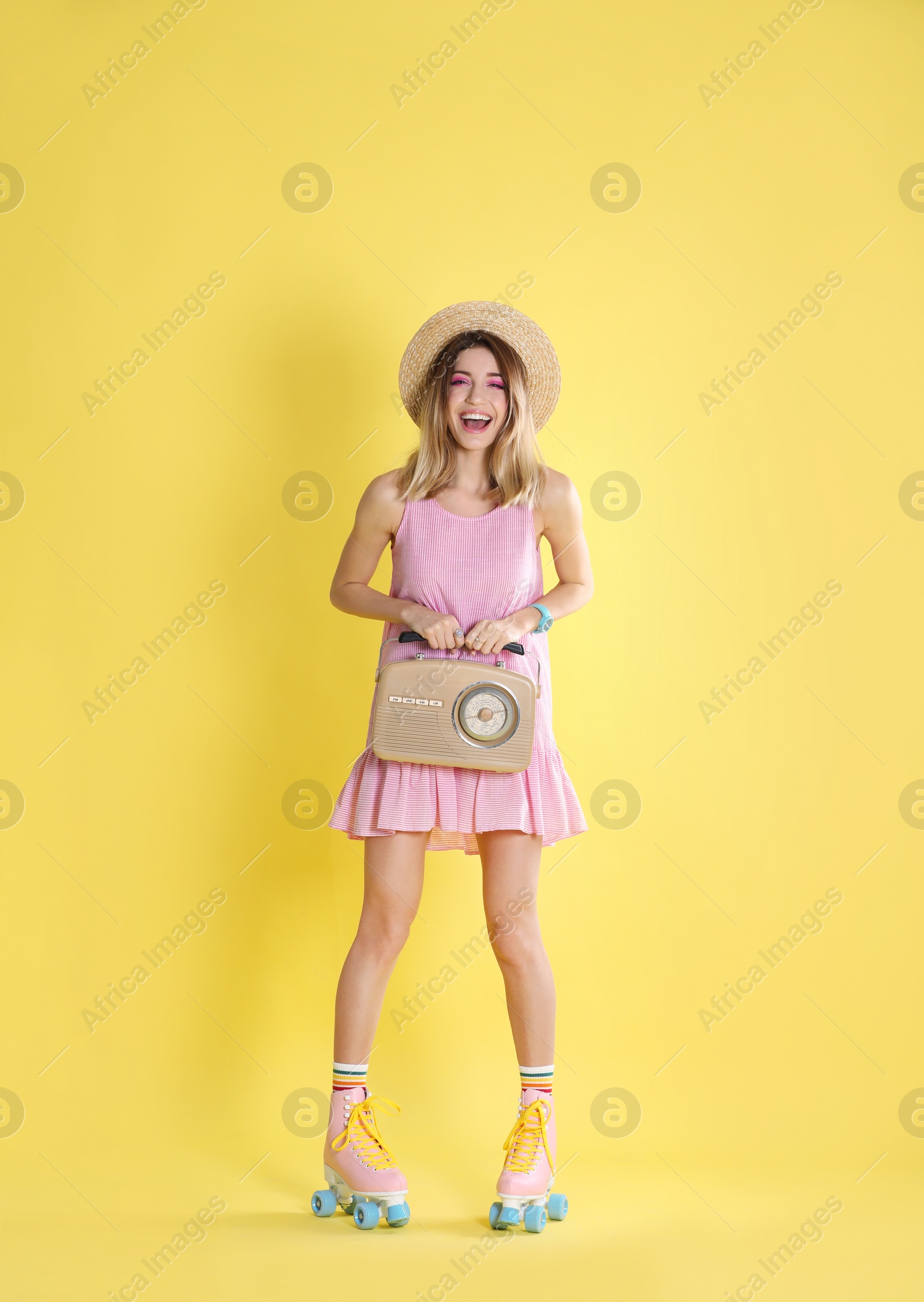 Photo of Young woman with roller skates and retro radio on color background