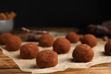 Photo of Delicious chocolate truffles powdered with cocoa on wooden table, closeup. Space for text