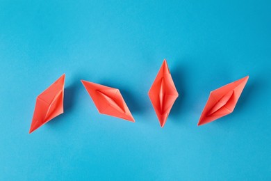 Photo of Handmade pink paper boats on light blue background, flat lay. Origami art