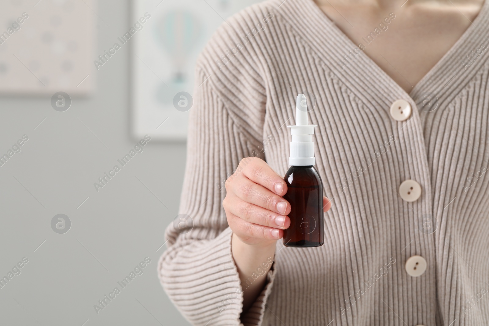 Photo of Woman holding nasal spray indoors, closeup. Space for text