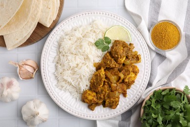 Photo of Delicious chicken curry with rice and ingredients on white tiled table, flat lay