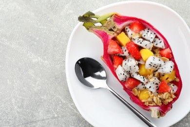 Photo of Yummy pitahaya boat with mango, granola and strawberry served on light grey table, top view. Space for text