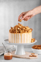 Woman decorating caramel drip cake at light table, closeup