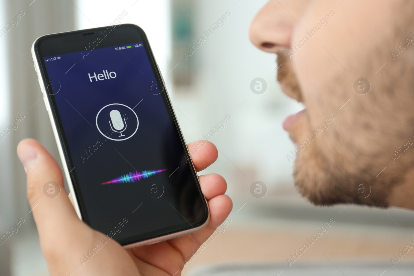 Photo of Young man using voice search on smartphone indoors, closeup