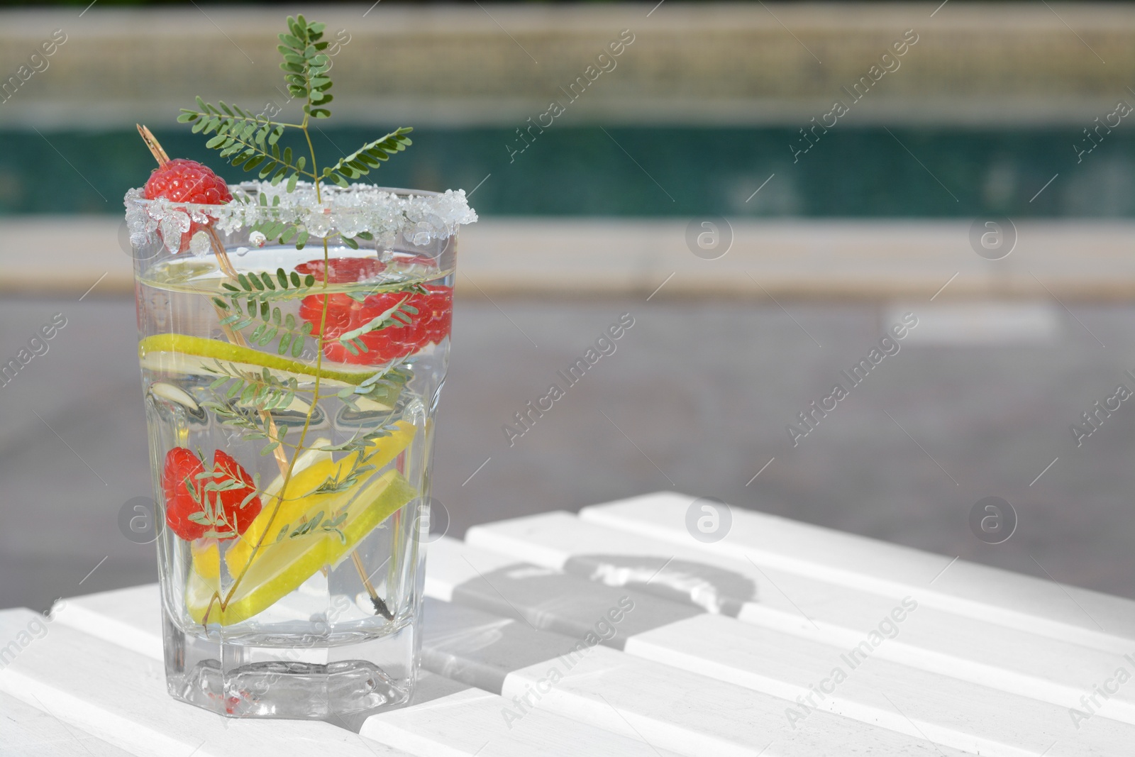 Photo of Delicious refreshing lemonade with raspberries on white wooden table outdoors, space for text
