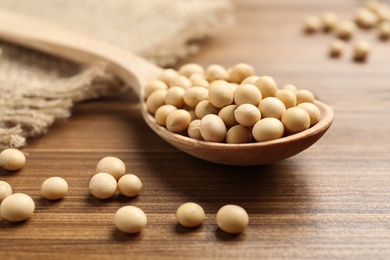 Photo of Soya beans with spoon on wooden table, closeup