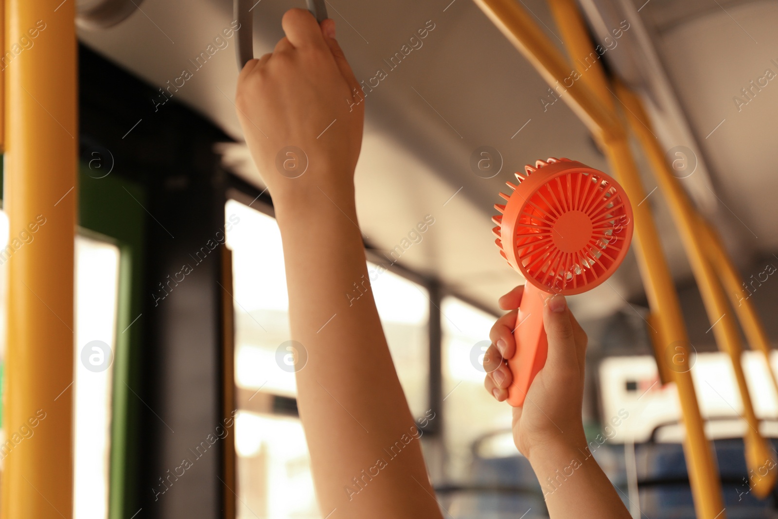 Photo of Woman with portable fan in bus, closeup. Summer heat