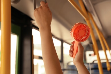 Photo of Woman with portable fan in bus, closeup. Summer heat