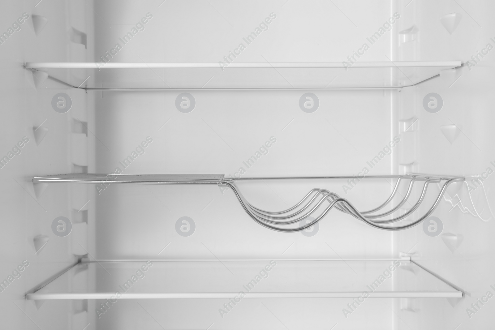 Photo of Modern open refrigerator with empty shelves, closeup