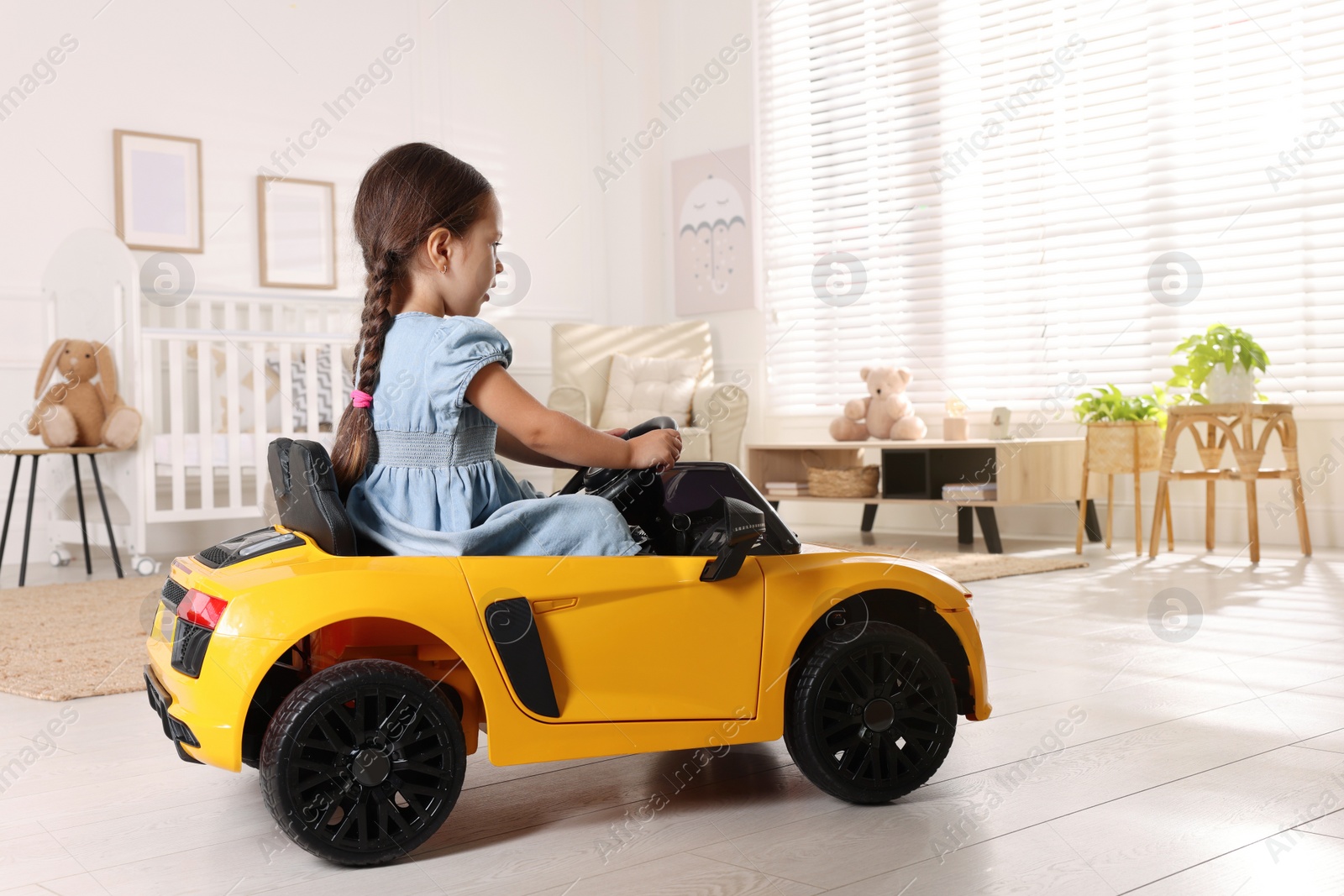 Photo of Adorable child driving toy car in room at home