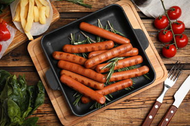 Photo of Tasty grilled sausages served on wooden table, flat lay