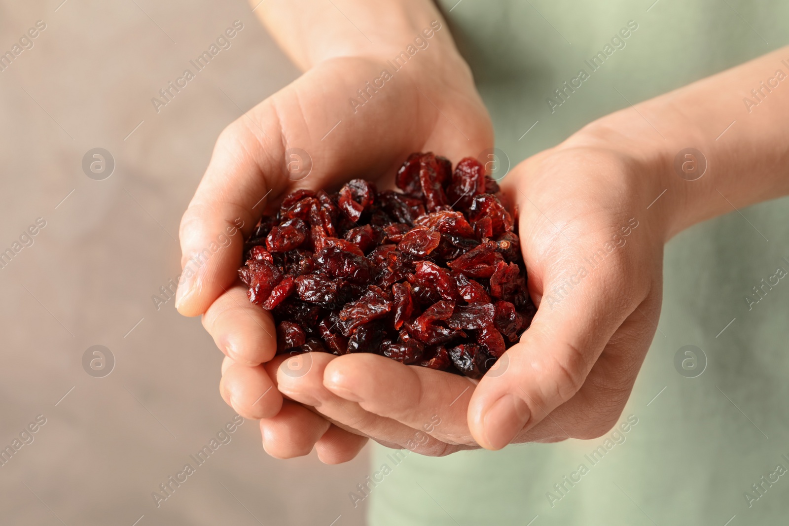 Photo of Woman holding handful of tasty cranberries on color background, closeup. Dried fruits as healthy snack