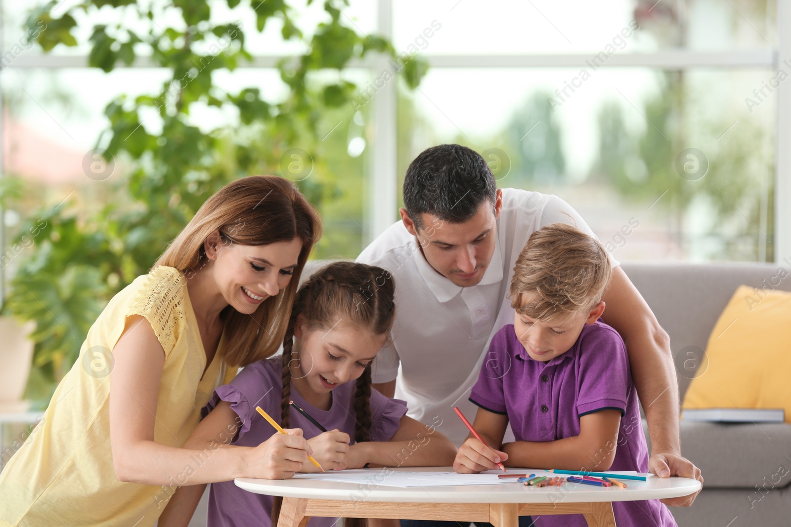 Photo of Children with parents drawing at table indoors. Happy family