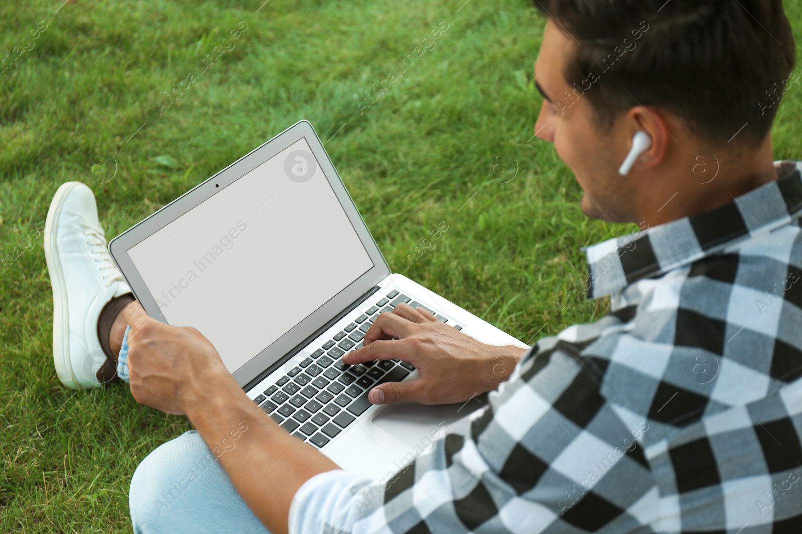 Photo of Portrait of young man with laptop outdoors. Space for design