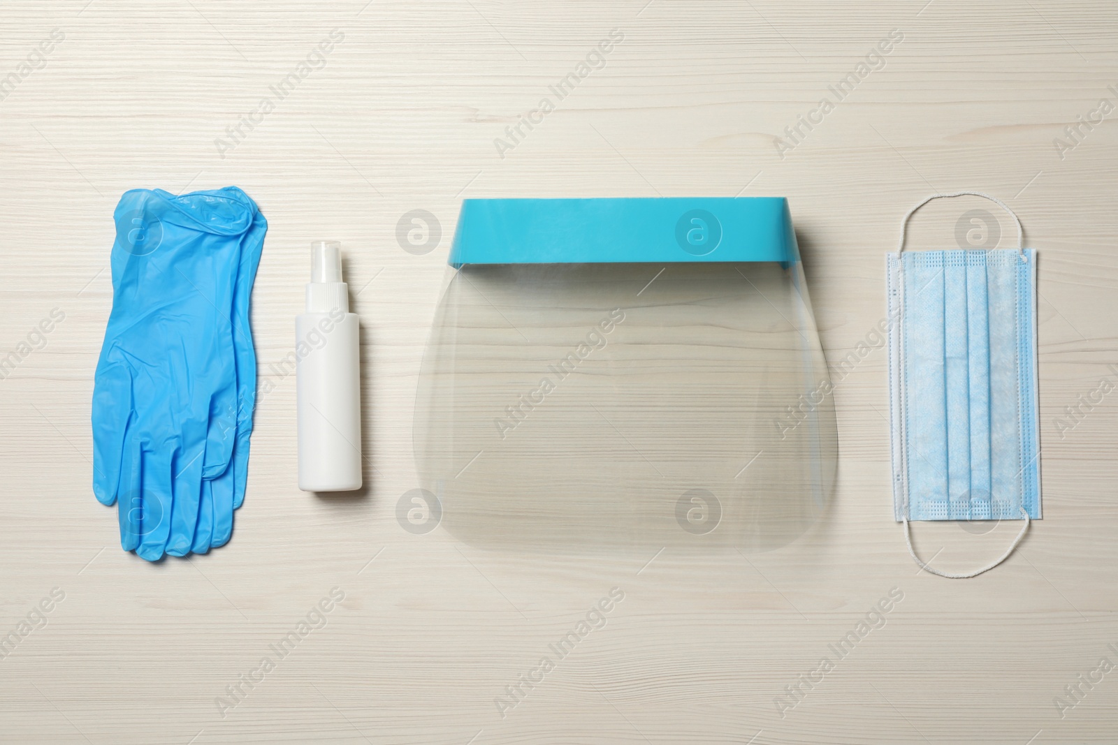 Photo of Medical gloves, hand sanitizer, mask and face shield on wooden background, flat lay. Safety equipment