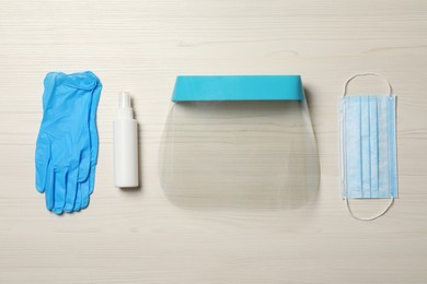 Photo of Medical gloves, hand sanitizer, mask and face shield on wooden background, flat lay. Safety equipment