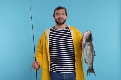 Photo of Fisherman with rod and catch on light blue background