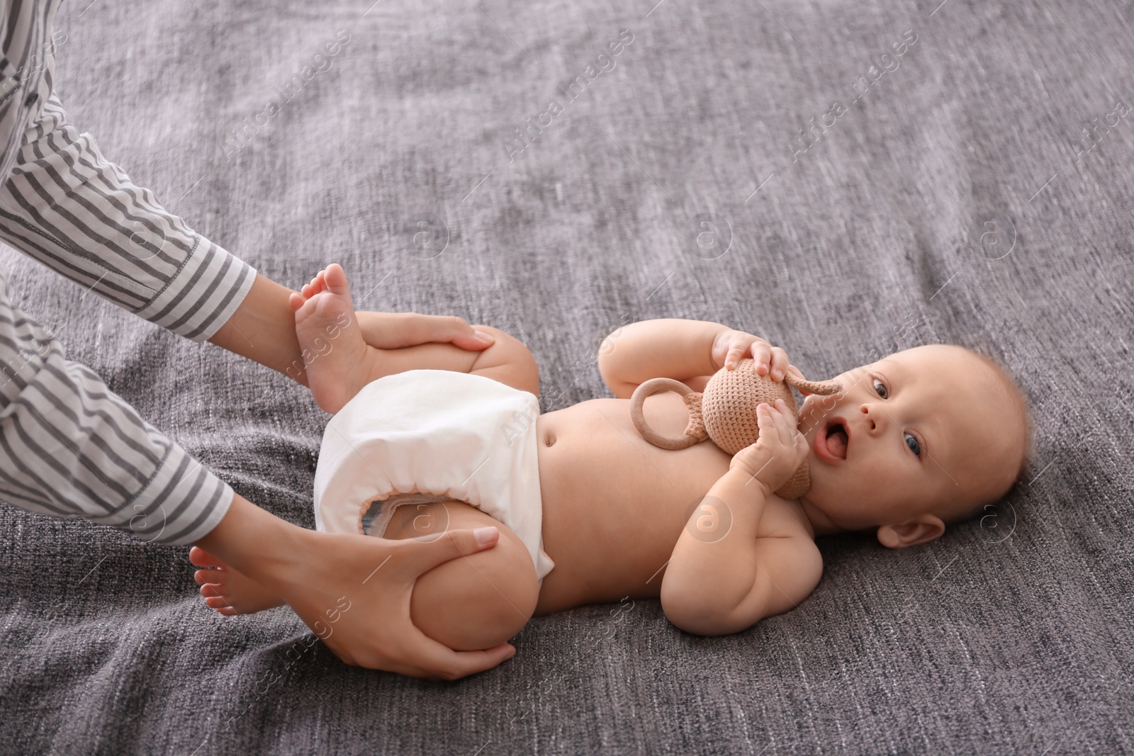 Photo of Young woman massaging cute little baby on blanket