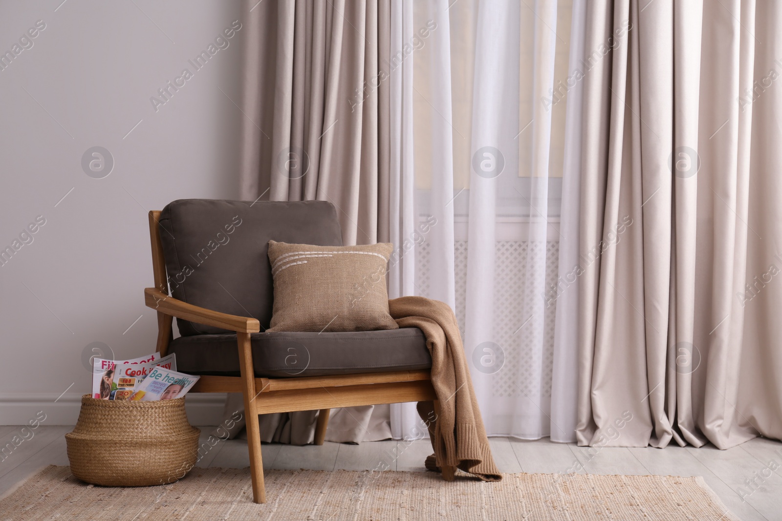 Photo of Comfortable armchair and wicker basket near window in living room. Interior design