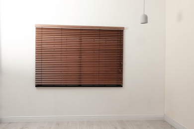 Photo of Modern window with closed stylish wooden blinds indoors. Space for text