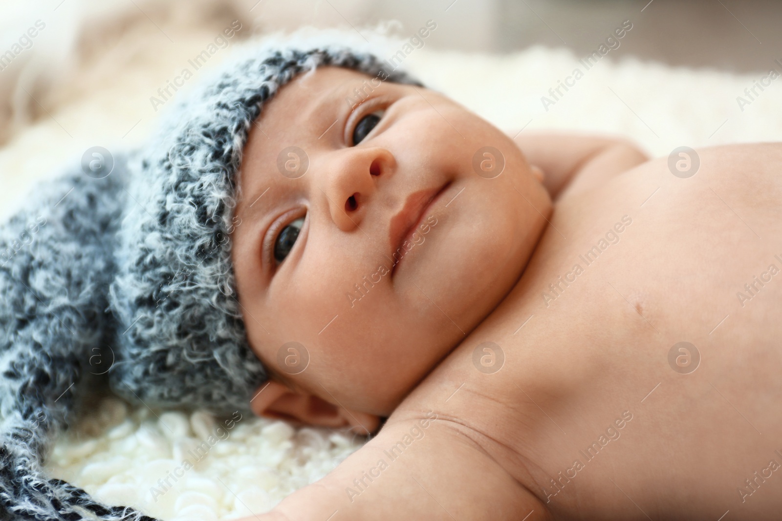 Photo of Cute little baby in grey hat lying on soft blanket