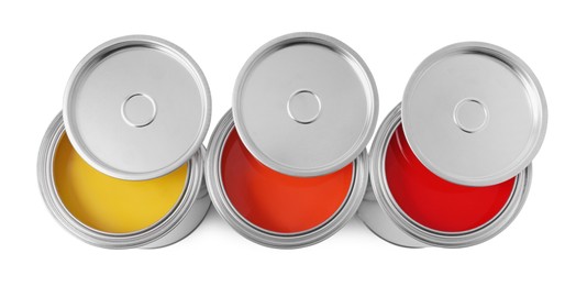 Photo of Cans of orange, yellow and red paints on white background, top view