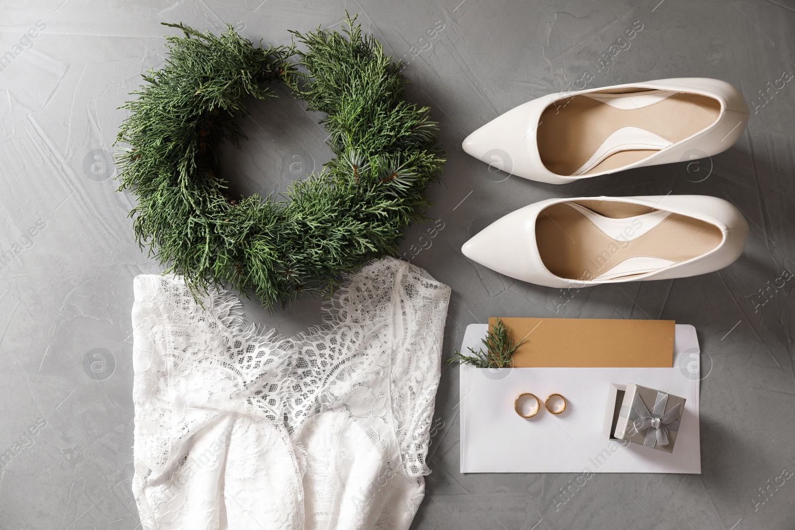 Photo of Flat lay composition with wedding dress, white high heel shoes and rings on grey background