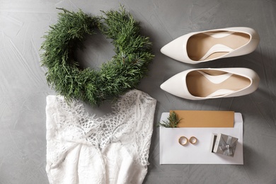 Flat lay composition with wedding dress, white high heel shoes and rings on grey background