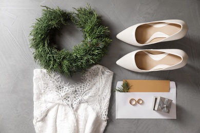 Photo of Flat lay composition with wedding dress, white high heel shoes and rings on grey background