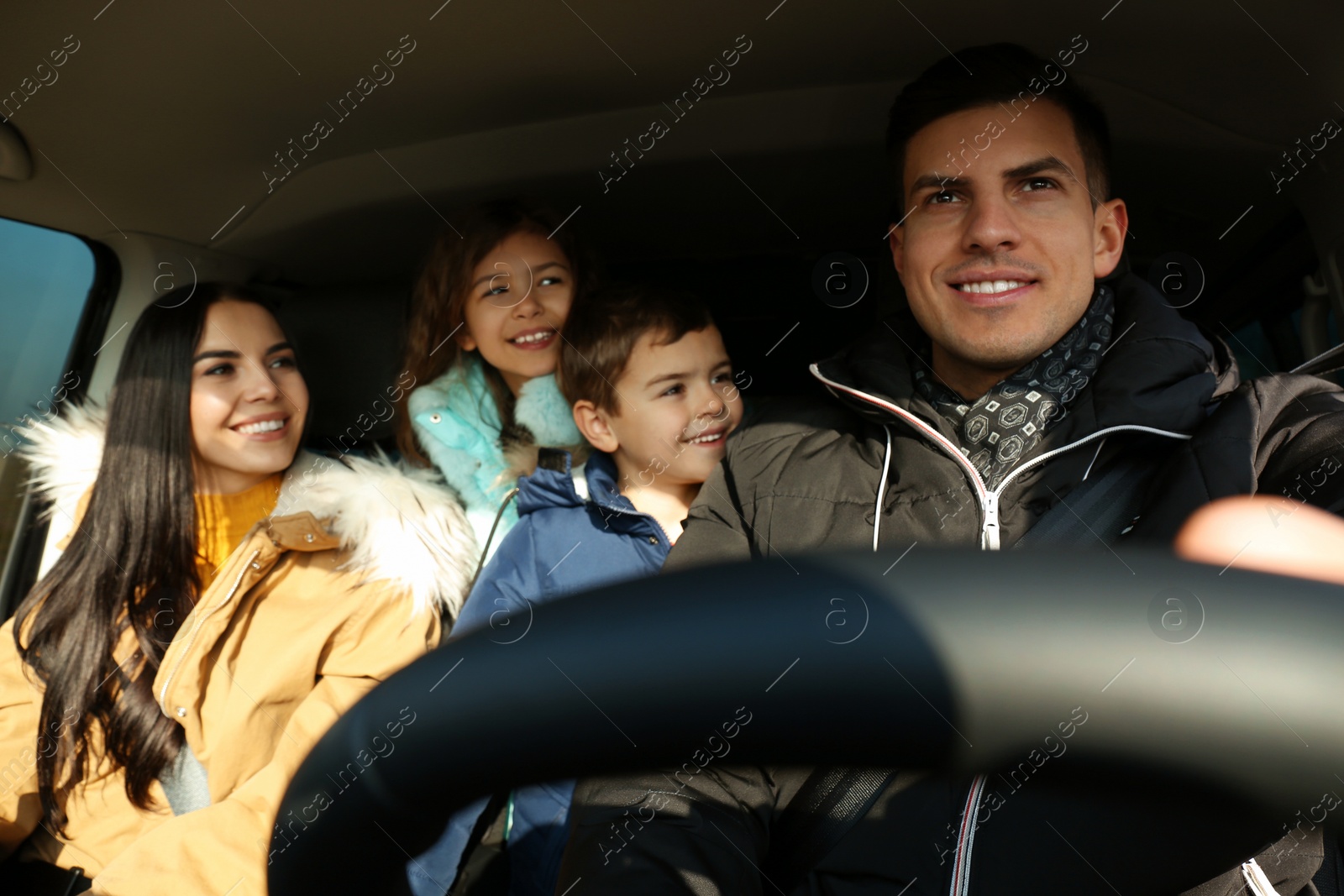 Photo of Happy family with little children inside modern car