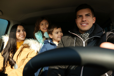 Happy family with little children inside modern car