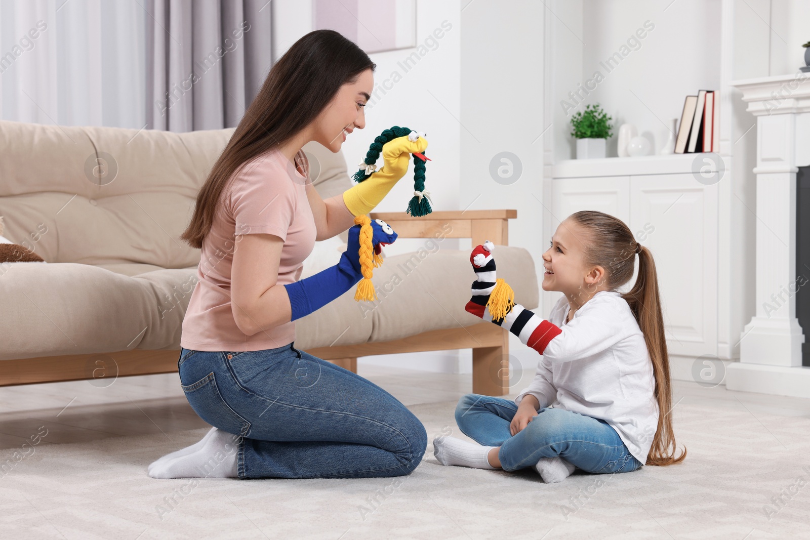 Photo of Happy mother and daughter playing with funny sock puppets together at home