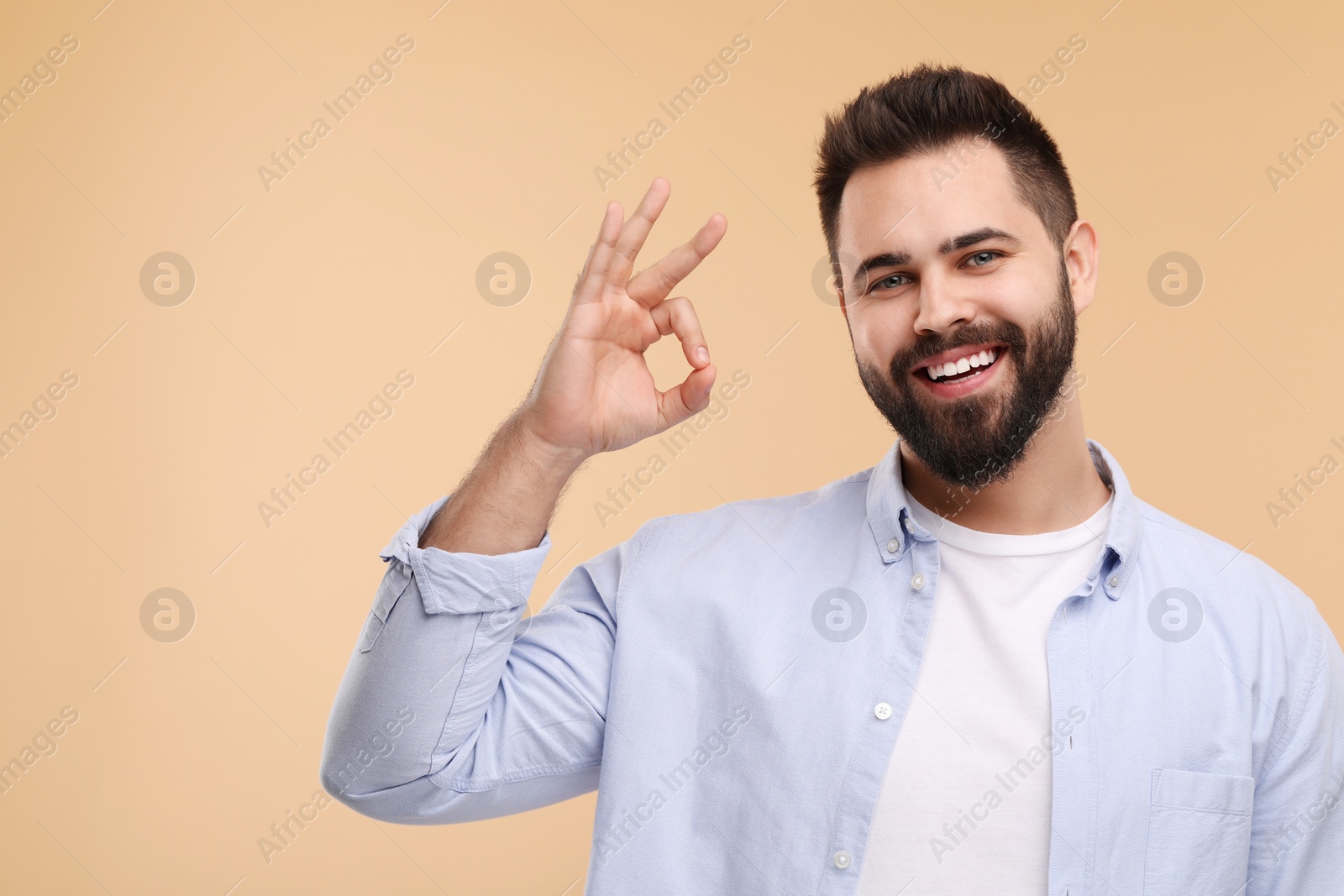 Photo of Man with clean teeth showing OK gesture on beige background, space for text