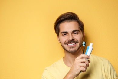 Photo of Portrait of young man with toothbrush and paste on color background. Space for text