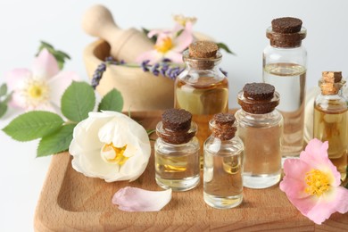 Photo of Aromatherapy. Different essential oils, flowers and green leaves on table