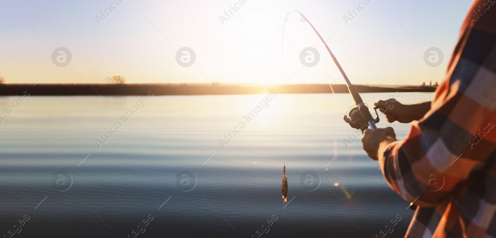 Image of Fisherman catching fish with rod at riverside, closeup view with space for text. Banner design