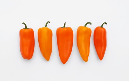 Fresh raw orange hot chili peppers on white background, flat lay