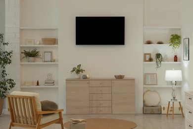 Stylish TV set mounted on wall in room