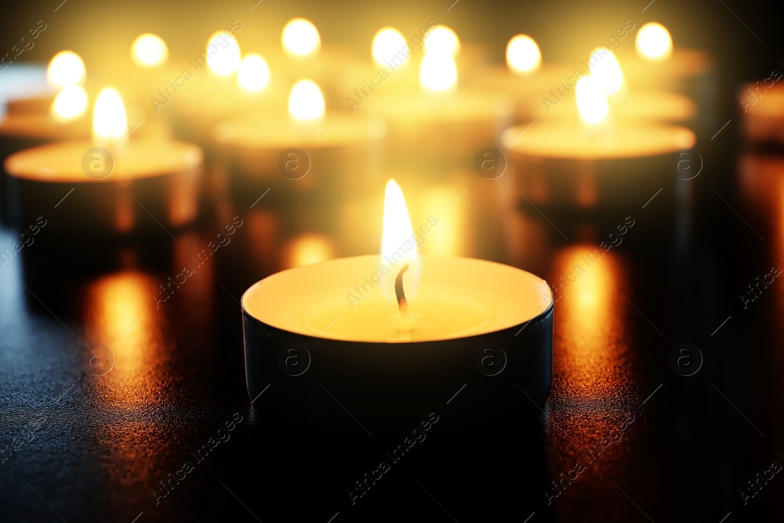 Photo of Wax candle burning on table in darkness, closeup