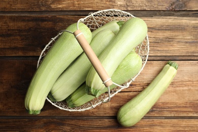 Photo of Basket with ripe zucchinis on wooden table, flat lay