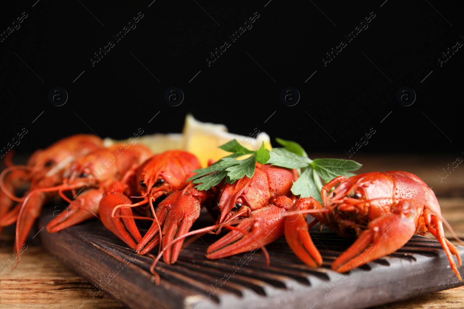 Photo of Delicious boiled crayfishes on wooden table, closeup