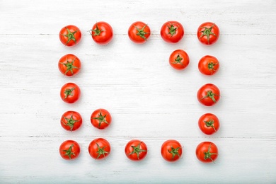 Photo of Frame made of ripe tomatoes on wooden background