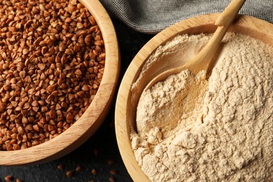 Photo of Buckwheat flour and grains in bowls on black table, top view