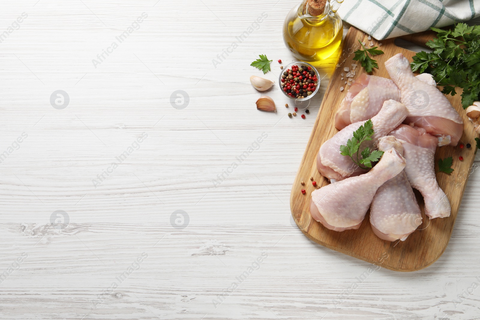 Photo of Raw chicken drumsticks and ingredients on white wooden table, flat lay. Space for text