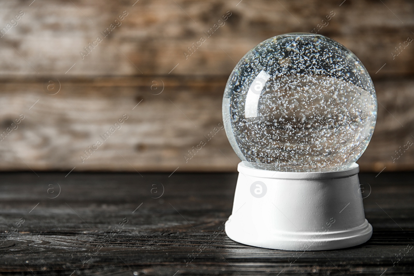 Photo of Magical empty snow globe on wooden table. Space for text